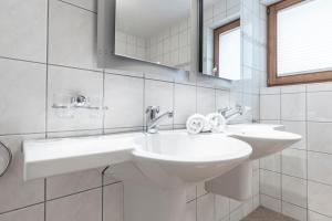 a white bathroom with two sinks and a mirror at Chasa Vaidum by MEIN SAMNAUN - MOUNTAIN HOMES in Samnaun +103 photos