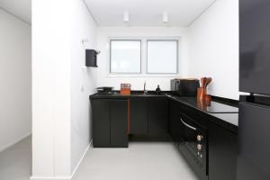 a black kitchen with a sink and a window at Tabas - Edifício Arinda - São Paulo in Sao Paulo