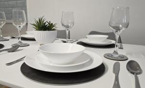 a table with a white bowl and plates and wine glasses at Kings Corner in Warrenpoint