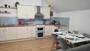 eine Küche mit weißen Schränken und einem Tisch mit Stühlen in der Unterkunft Kings Corner in Warrenpoint