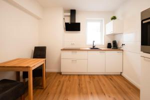 a kitchen with white cabinets and a wooden table at RandHome Apartment Erwitte Horn, Bad Sassendorf in Erwitte +24 photos
