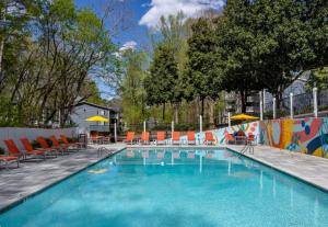 une grande piscine avec chaises et parasols dans l'établissement Crest At East Cobb 1830 Sleek & Cozy 2bd 2bt, à Marietta