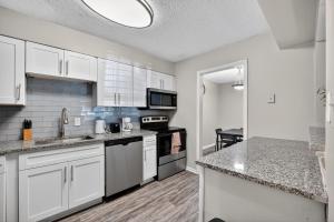 une cuisine avec des armoires blanches et un four à plaques de cuisson dans l'établissement Crest At East Cobb 1830 Sleek & Cozy 2bd 2bt, à Marietta