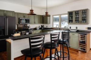 a kitchen with green cabinets and a large island with bar stools at Southfork Retreat in Big Sky