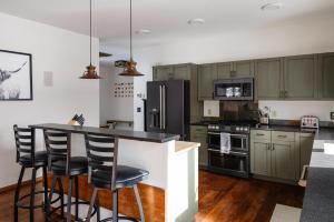 a kitchen with green cabinets and a island with bar stools at Southfork Retreat in Big Sky