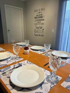 a wooden table with plates and glasses on it at Solarium Riviera - Casa2 - NOVA 600m praia Riviera in Matinhos