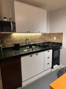 a kitchen with white cabinets and a sink and a stove at Solarium Riviera - Casa2 - NOVA 600m praia Riviera in Matinhos