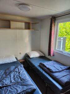 ein kleines Zimmer mit zwei Betten und einem Fenster in der Unterkunft La Petite Maison du Park in Boofzheim