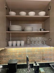 a kitchen with plates and bowls on a shelf at Solarium Riviera - Casa2 - NOVA 600m praia Riviera in Matinhos
