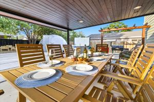 uma mesa de madeira com pratos e copos de vinho num pátio em Luxe Family Escape with Games and Hot Tub and Yard em San Antonio mais 60 fotografias