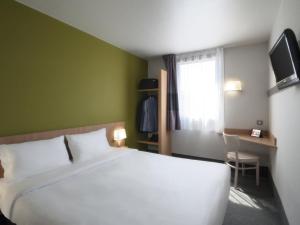 - une chambre avec un grand lit blanc et une fenêtre dans l'établissement B&B HOTEL Paray-le-Monial, à Paray-le-Monial