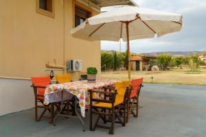 a table and chairs with an umbrella on a patio at Fotini's Holiday Beach Home in Dhíkella