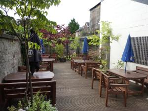 a patio with wooden tables and blue umbrellas at The Douglas Hotel in Langholm