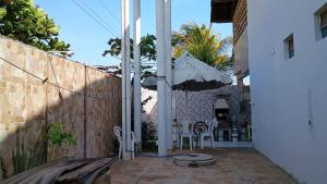 a patio with a fence and an umbrella at Casa com 5 suítes e Churrasqueira para 12 pessoas in Atalaia