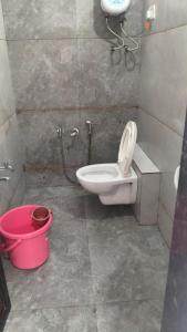 a bathroom with a toilet and a pink bucket at Nilkanth Bunglows in Garudeshwar