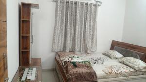 a bedroom with a bed and a window with curtains at Nilkanth Bunglows in Garudeshwar +3 photos