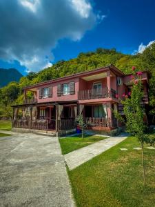 a large red house with a hill in the background at Apartments Djurovic in Virpazar