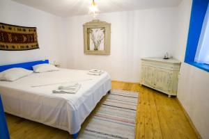 a bedroom with a white bed and a dresser at La Lipoveni in Jurilovca