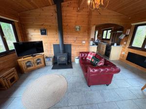 a living room with a red leather couch and a fireplace at Brynmeini Lake Lodge 