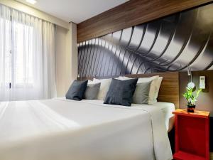 a bedroom with a large white bed with blue pillows at Mercure Sao Paulo Moema Times Square in Sao Paulo