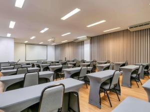 an empty classroom with tables and chairs and a whiteboard at Mercure Belo Horizonte Vila da Serra in Belo Horizonte +159 photos