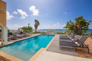 une piscine avec des chaises longues et l'océan dans l'établissement Oceanfront Colonial Villa with Pool, à Willemstad