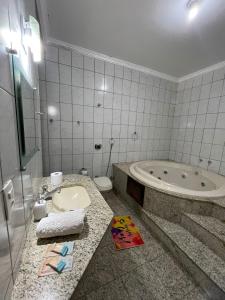 a bathroom with a tub and a sink and a toilet at Hostel Castelo in Belo Horizonte