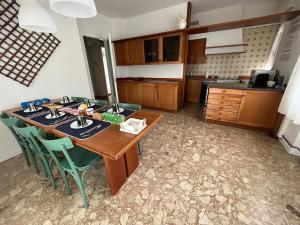 Una cocina con una mesa de madera y sillas verdes. en appartamento vicinissimo al centro, en Udine
