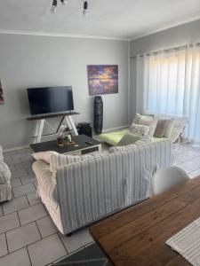 a living room with a couch and a flat screen tv at Starfish Cottage in Langebaan