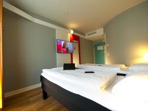duas camas em um quarto com uma tv na parede em ibis Köln Messe em Colónia