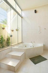 a white bathroom with a tub and a window at por do sol na montanha in Guaratinguetá