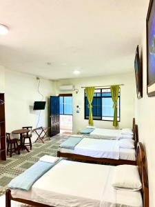 a hotel room with three beds and a table at Hostal Gardner in Puerto Ayora +46 photos
