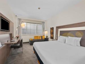a hotel room with a large bed and a desk at Novotel Dubai World Trade Centre in Dubai