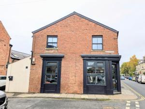 a brick building with black doors on a street at Old Yarn Apartment - Close to city walls in York