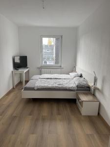 a white bedroom with a bed and a television at Wupper Apartments Vogel in Erbschlö