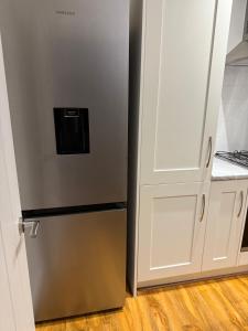 a stainless steel refrigerator next to a white cabinet at Large Double Room in Longbridge