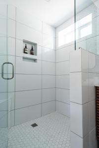 a white bathroom with a shower with two bottles at Simple La Jolla Epic bungalow #7 in San Diego
