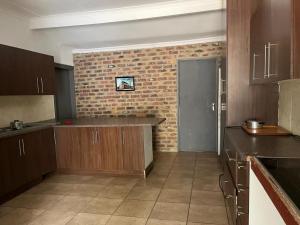 una cocina con armarios de madera y una pared de ladrillo en NelsBNB, en Nelspruit 4 fotos más
