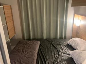 1 cama en un dormitorio con cortina verde en Mobil home 6 personne, en La Tranche-sur-Mer 4 fotos más