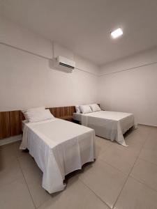 two beds with white sheets in a room at Boulevard Hotel Crateús in Crateús