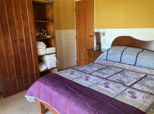 a bedroom with a bed with a purple bedspread at Casa de playa Camping Chajarí in Santa Ana
