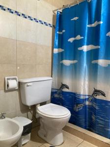 a bathroom with a toilet and a blue shower curtain at Casa de playa Camping Chajarí in Santa Ana
