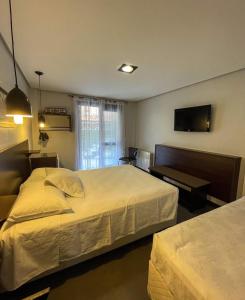 a hotel room with two beds and a flat screen tv at Pousada Araucárias in Canela