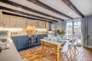 a kitchen with blue cabinets and a wooden table at Green Side Cottage in Thornham