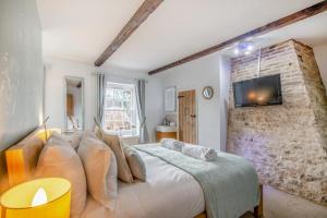 索海姆Green Side Cottage的卧室配有1张床和1台砖墙电视