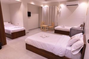 una habitación de hotel con dos camas y una mesa en Arkan Hotel Qena, en Qinā