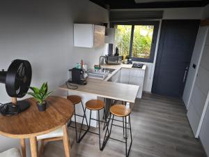 a small kitchen with a table and stools in a room at Ataoaoa iti Bungalow à Punaauia in Punaauia +7 photos