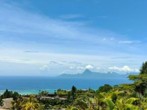a view of the ocean with mountains in the background at Ataoaoa iti Bungalow à Punaauia in Punaauia