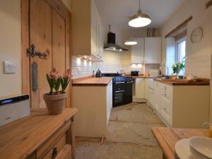 a large kitchen with white cabinets and black appliances at 2 bed property in Ilminster Somerset 56523 in Ilminster