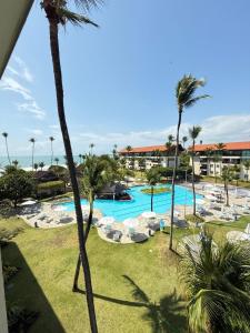 a view of a resort swimming pool with palm trees at Estúdio Marulhos, varanda com vista de mar e parque aquático, à beira-mar de Muro Alto, wi-fi, restaurante, estacionamento e a 10' de Porto de Galinhas in Porto De Galinhas